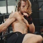 A shirtless man kicks a kick in a boxing ring