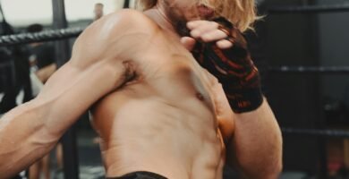 A shirtless man kicks a kick in a boxing ring