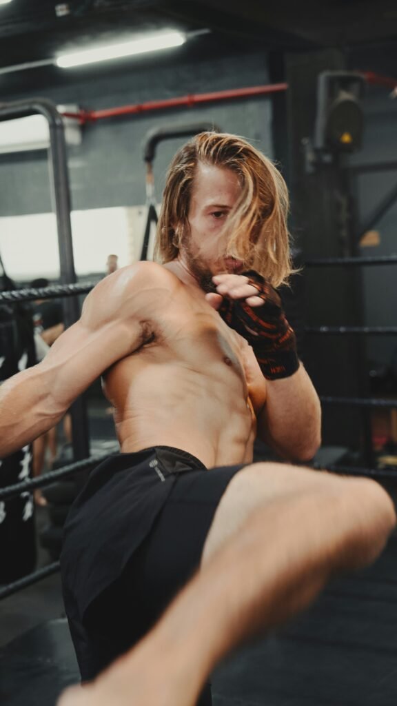 A shirtless man kicks a kick in a boxing ring